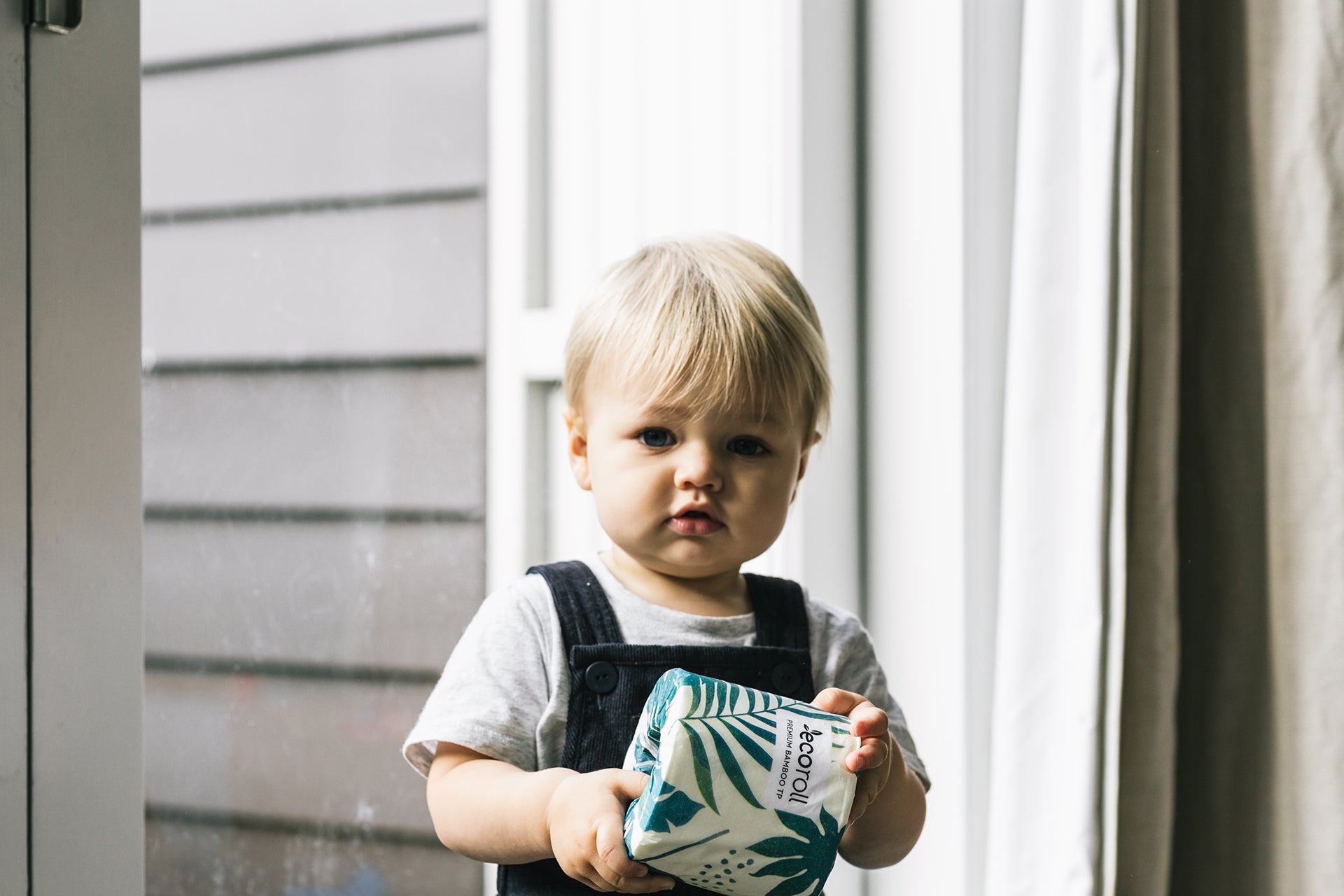 Image of a toddler, holding a sustainable toilet paper roll